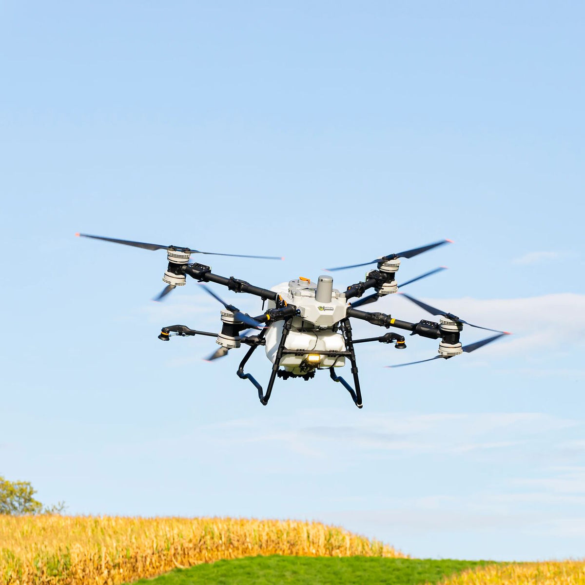 DJI Agras T100 spray drone in flight over a field